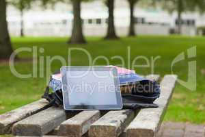 Purple schoolbag and tablet lying on park bench