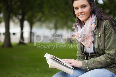 Gleeful brunette student sitting on bench reading