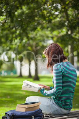 Casual student sitting on bench reading
