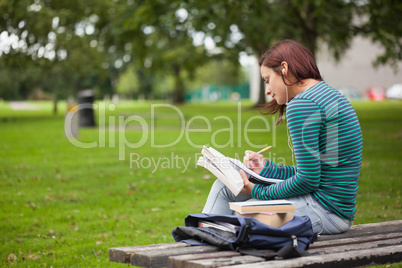 Serious casual student sitting on bench taking notes