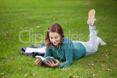 Content casual student lying on grass reading