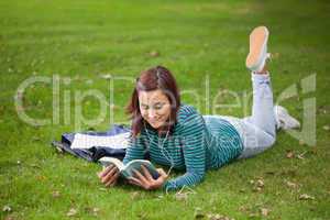 Content casual student lying on grass reading