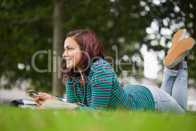 Smiling casual student lying on grass looking away