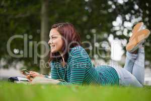 Smiling casual student lying on grass looking away