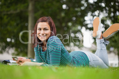 Smiling casual student lying on grass looking at camera