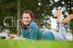 Smiling casual student lying on grass looking at camera