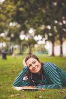 Smiling casual student lying on grass looking up