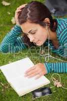 Calm casual student lying on grass reading a book