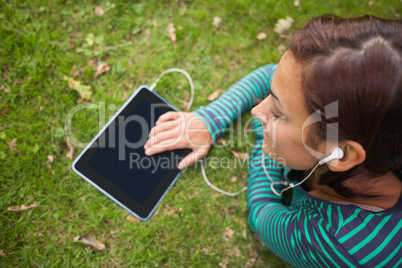 Casual student lying on grass using tablet
