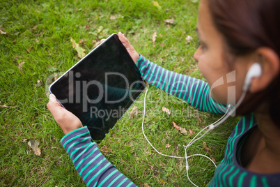 Casual student lying on grass holding tablet