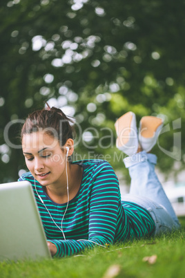 Content casual student lying on grass using laptop