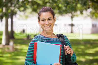 Casual cheerful student looking at camera holding books