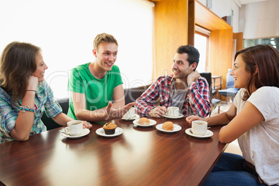 Four casual students having a cup of coffee chatting