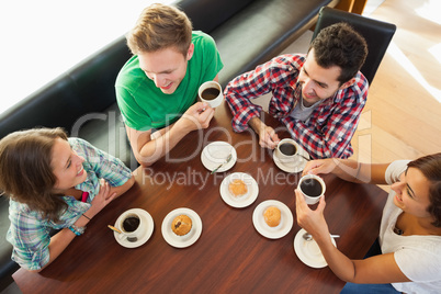 Four smiling students having a cup of coffee chatting