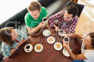 Four smiling students having a cup of coffee chatting