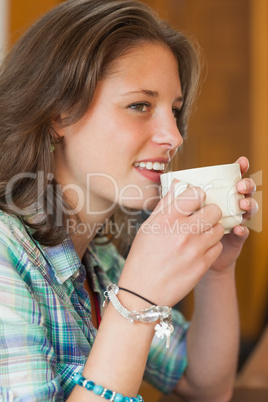 Pretty cheerful student drinking a cup of coffee