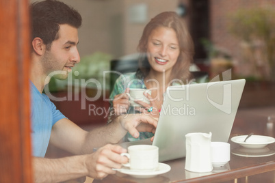 Two laughing students working at laptop