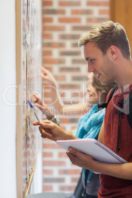 Smiling students searching something on notice board