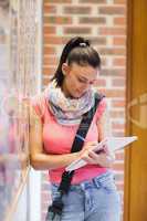 Attractive smiling student taking notes next to notice board