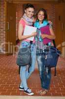 Two happy students posing in hallway