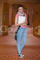 Pretty cheerful student standing in hallway