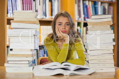 Exhausted pretty student studying between piles of books