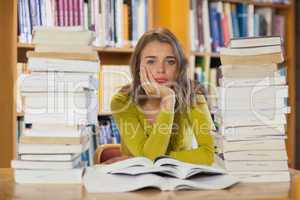 Exhausted pretty student studying between piles of books