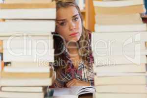 Stern pretty student studying between piles of books