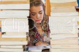 Concentrated pretty student studying between piles of books