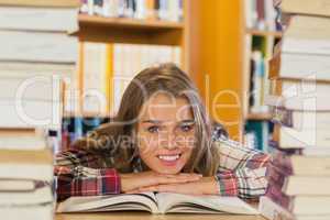 Smiling pretty student studying between piles of books