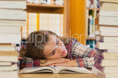 Tired pretty student resting head on table between piles of book