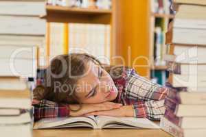 Tired pretty student resting head on table between piles of book