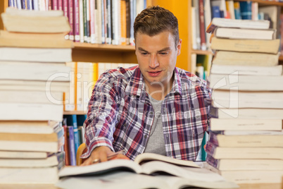 Handsome student studying between piles of books