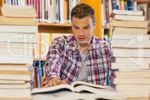 Handsome student studying between piles of books