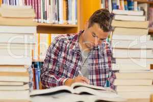 Focused handsome student studying between piles of books