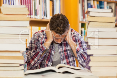 Concentrated handsome student studying between piles of books