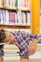 Exhausted handsome student resting head on piles of books