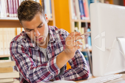 Handsome serious student pointing at computer