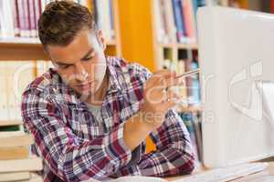 Handsome serious student pointing at computer