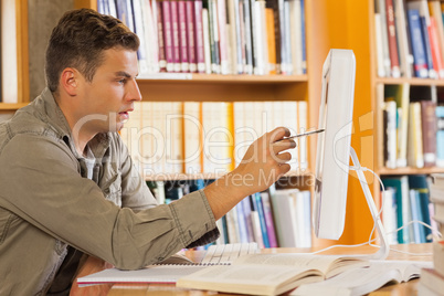 Handsome focused student pointing at computer