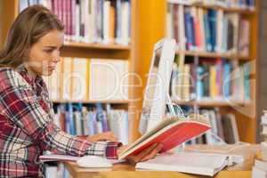 Pretty focused student reading book using computer