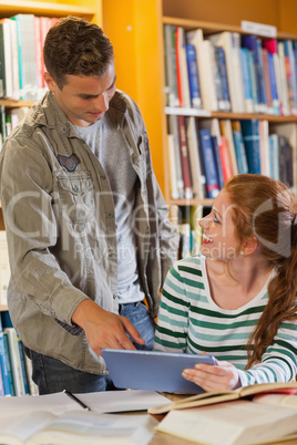 Two happy students studying together using tablet