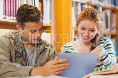 Two cheerful students studying together using tablet