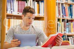 Attractive smiling student using tablet and holding book