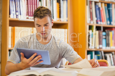 Attractive focused student using tablet and turning page