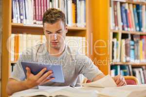 Attractive focused student using tablet and turning page