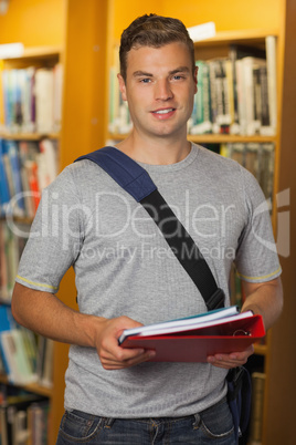 Handsome smiling student holding folder and notebooks