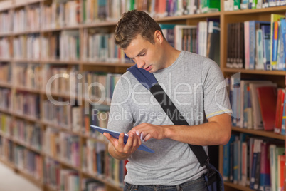 Handsome unsmiling student looking at tablet