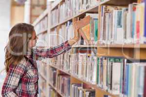 Pretty student placing book in shelf