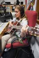 Concentrating pretty singer recording and playing guitar